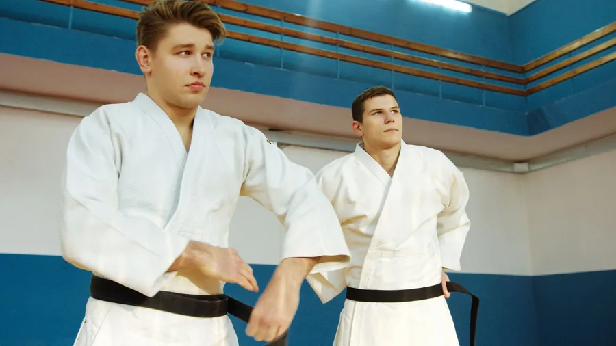 Two adult black belts in white gis practicing a technique